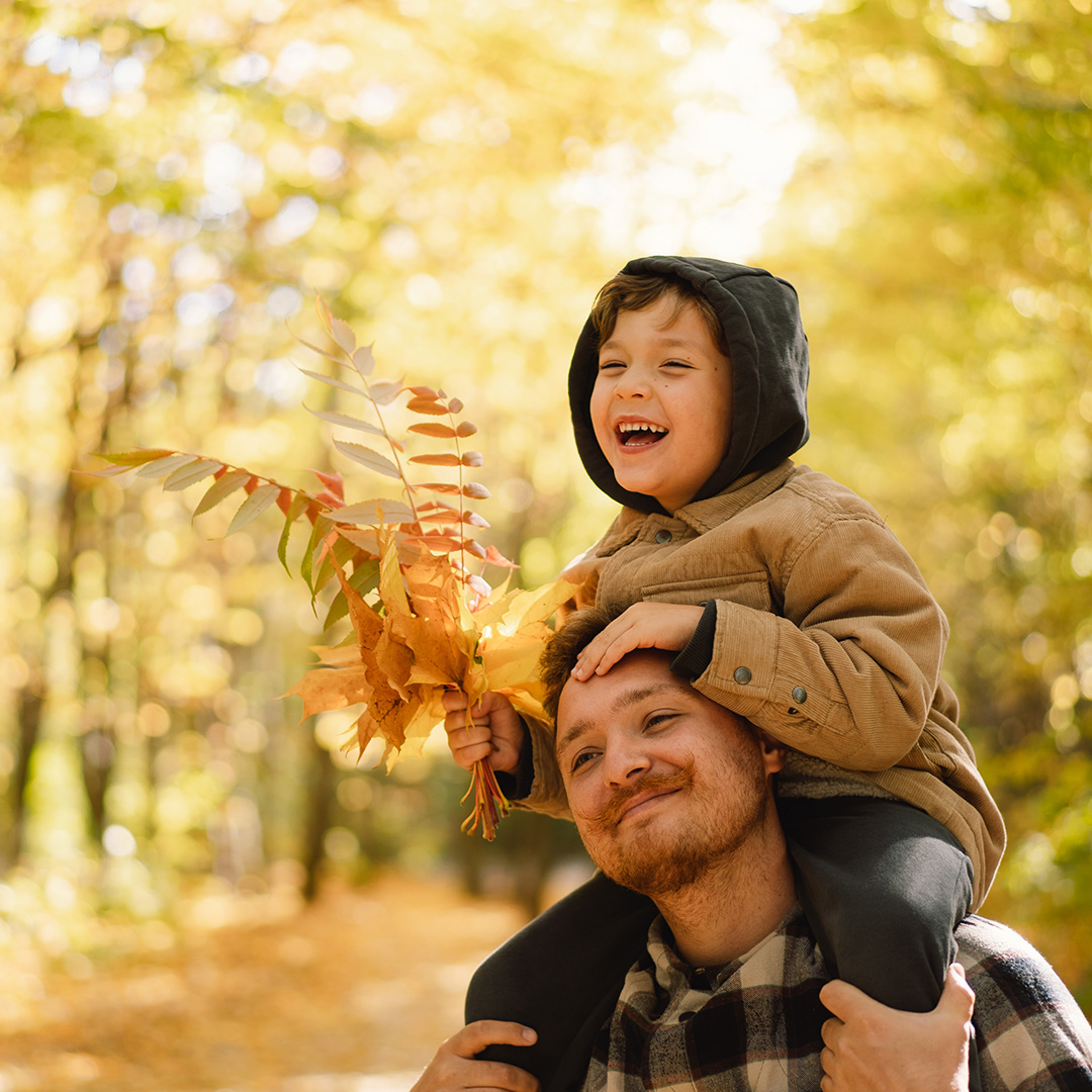 Father carrying his laughing son on his shoulders during a fall walk on a Blue Ridge Parkway road trip. Father carrying his laughing son on his shoulders during a fall walk on a Blue Ridge Parkway road trip.