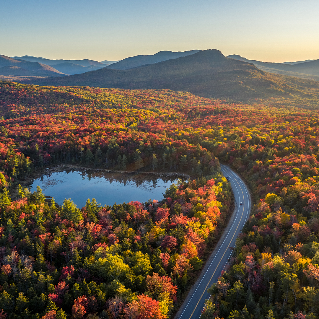 Overhead view of the Kancamagus Highway in New Hampshire, winding through the fall colors of White Mountain National Forest.