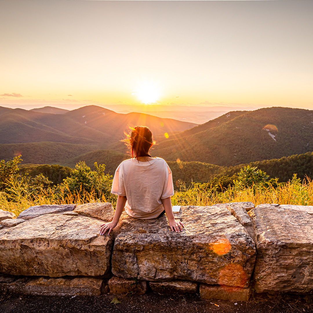 Traveler watching sunset over the Blue Ridge Mountains from the Shenandoah Skyline Drive overlook in Virginia.